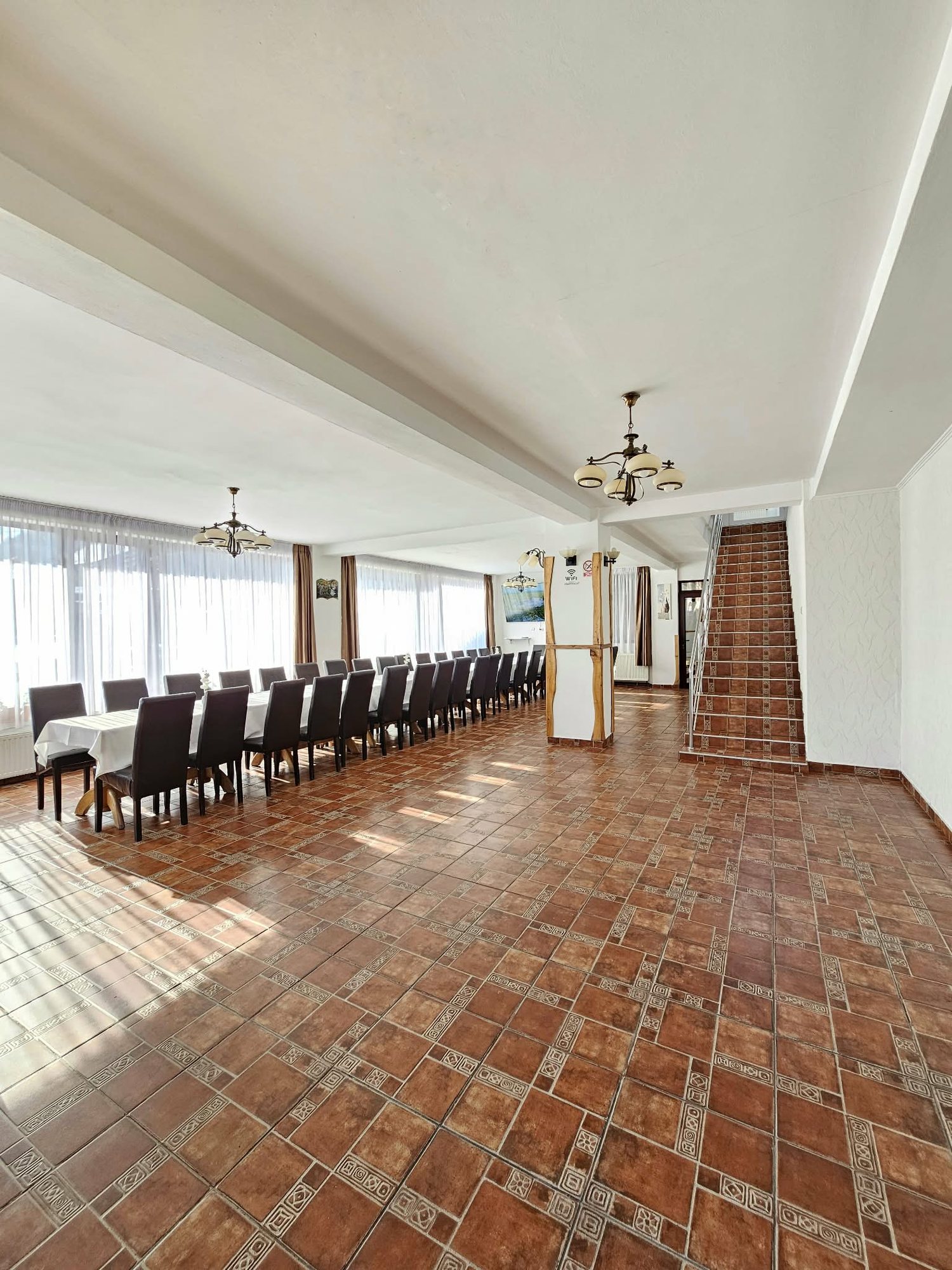 Salonul Vilei Enescu pregătit pentru un eveniment, cu mese lungi pentru 40 de persoane